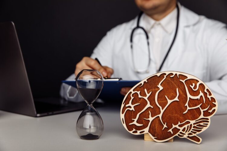 Wooden brain and hourglass in doctor's office. The importance of early diagnosis concept.