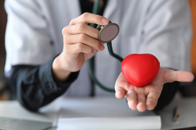 Doctor with stethoscope holding red heart in his hand. Healthcare and medical concept.